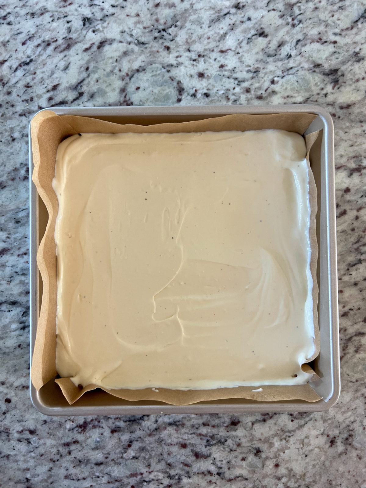 The cheesecake filling is spread over the graham cracker crust in the baking pan. 