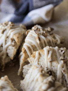 A closeup of three sourdough maple pecan scones with maple icing drizzled on top.
