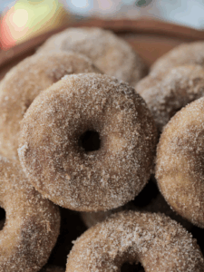 Closeup of a sourdough apple cider donut with many in the background.