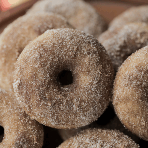Closeup of a sourdough apple cider donut with many in the background.