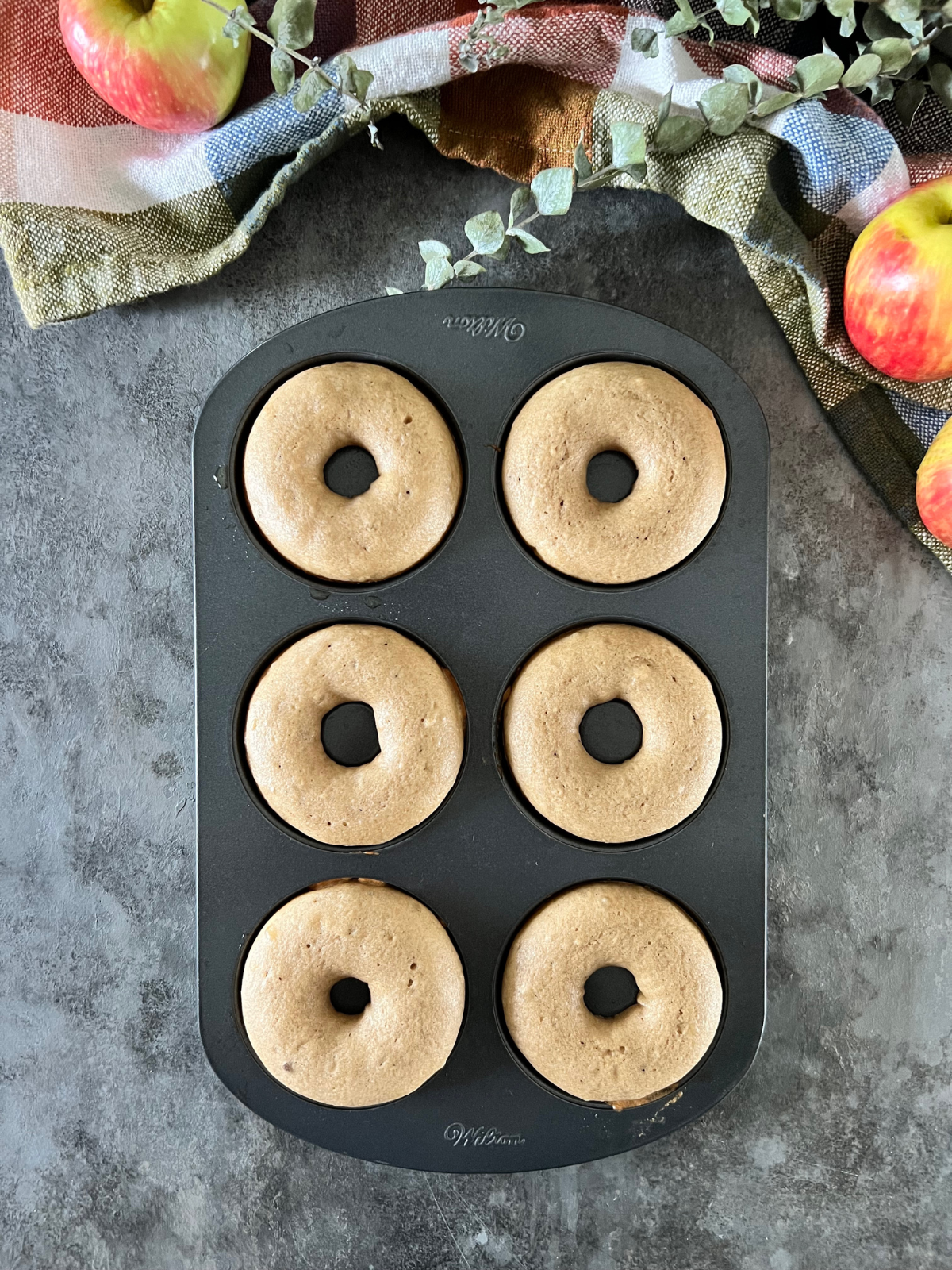 The donut pan sits on the counter with the baked donuts in it.