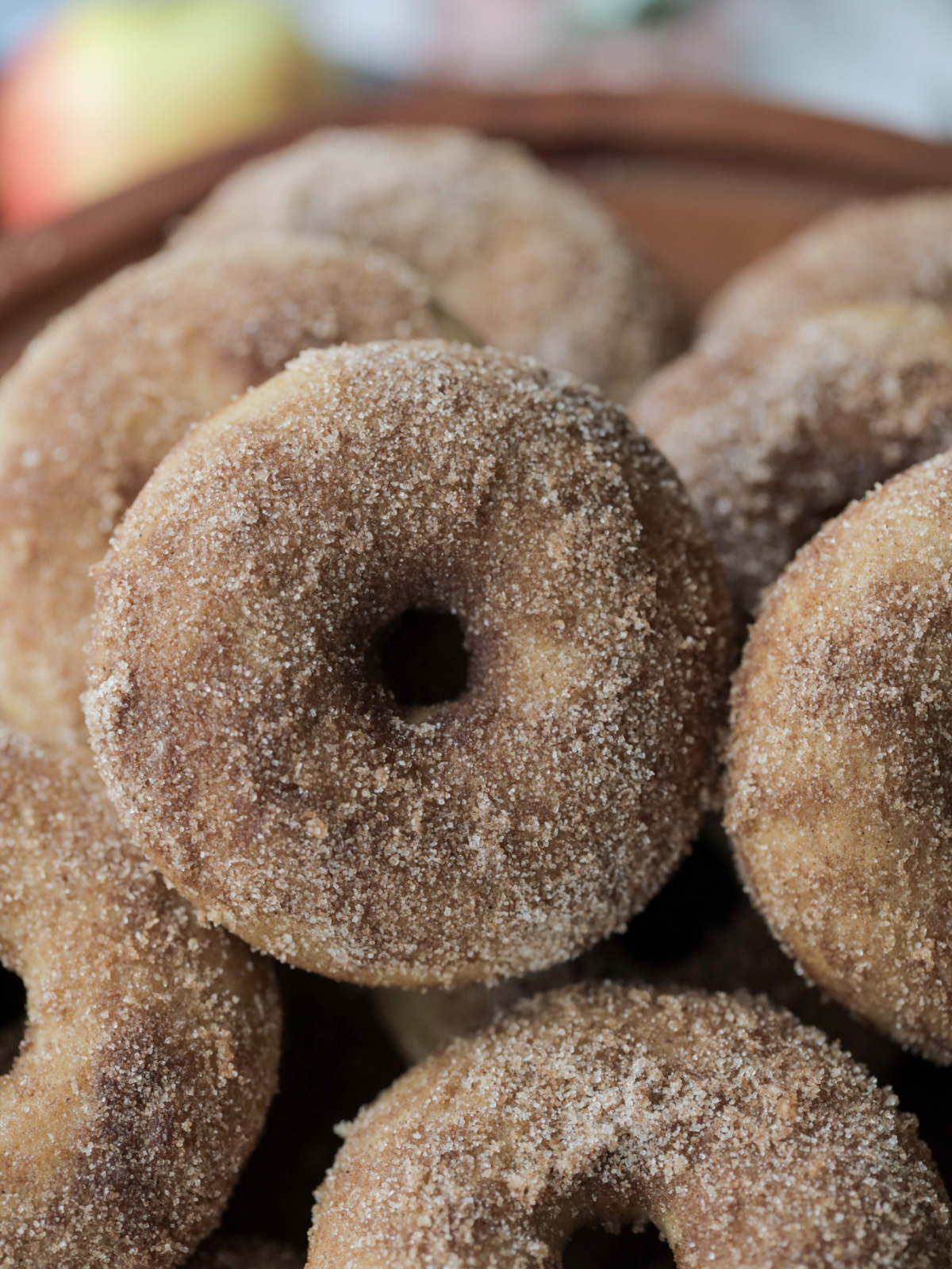 Closeup of a sourdough apple cider donut with many in the background.