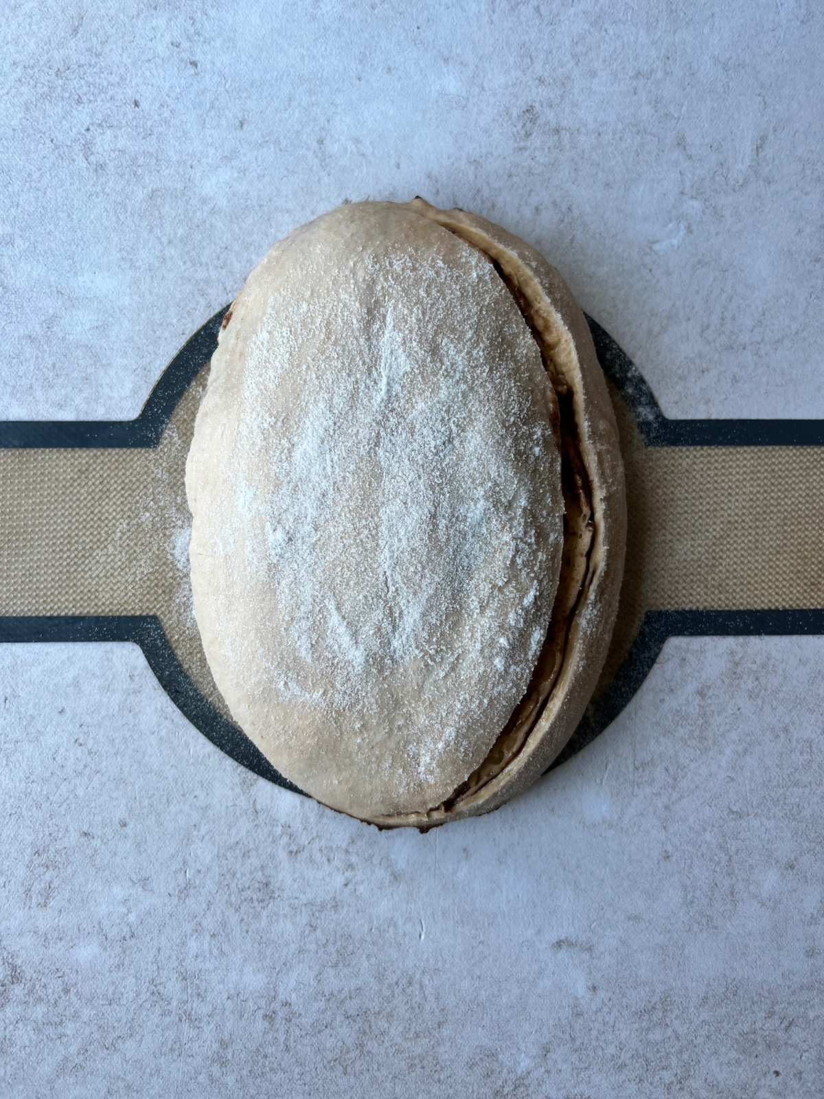 The dough sits on a bread sling after the overnight fermentation. The bread dough is scored.