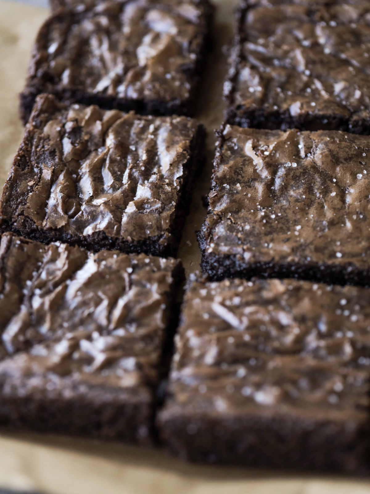 Fudgy brown butter brownies are cut in squares and sit on parchment paper. 