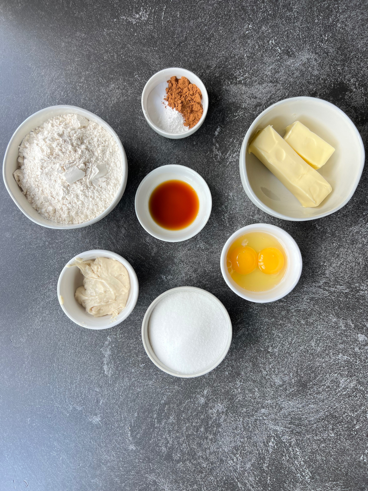 Ingredients for the sourdough snickerdoodle cookie recipe: all-purpose flour, cream of tartar, baking soda, salt, ground cinnamon, salted butter, granulated sugar, sourdough discard, one egg and one egg yolk, vanilla extract, and granulated sugar and ground cinnamon for rolling the dough balls in.