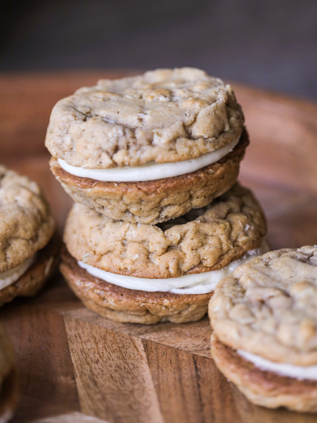 Two sourdough oatmeal cream pie sandwiches stacked on top of one another. There are other sourdough discard oatmeal cream pies surrounding them.