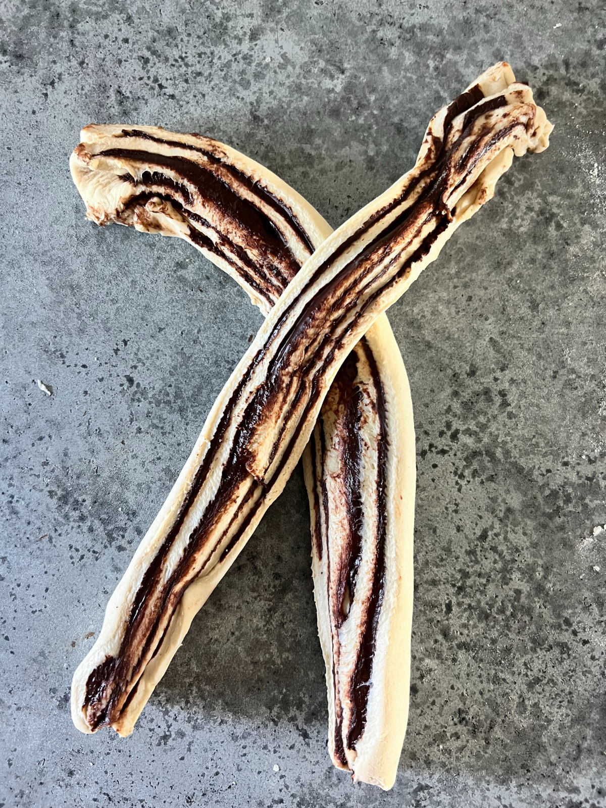 The cylinder of dough has been cut in half lengthwise and shows the two pieces of dough to be folded over each other.