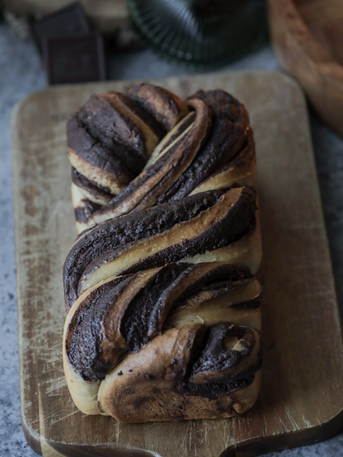 The baked chocolate sourdough babka sits on a wooden cutting board.
