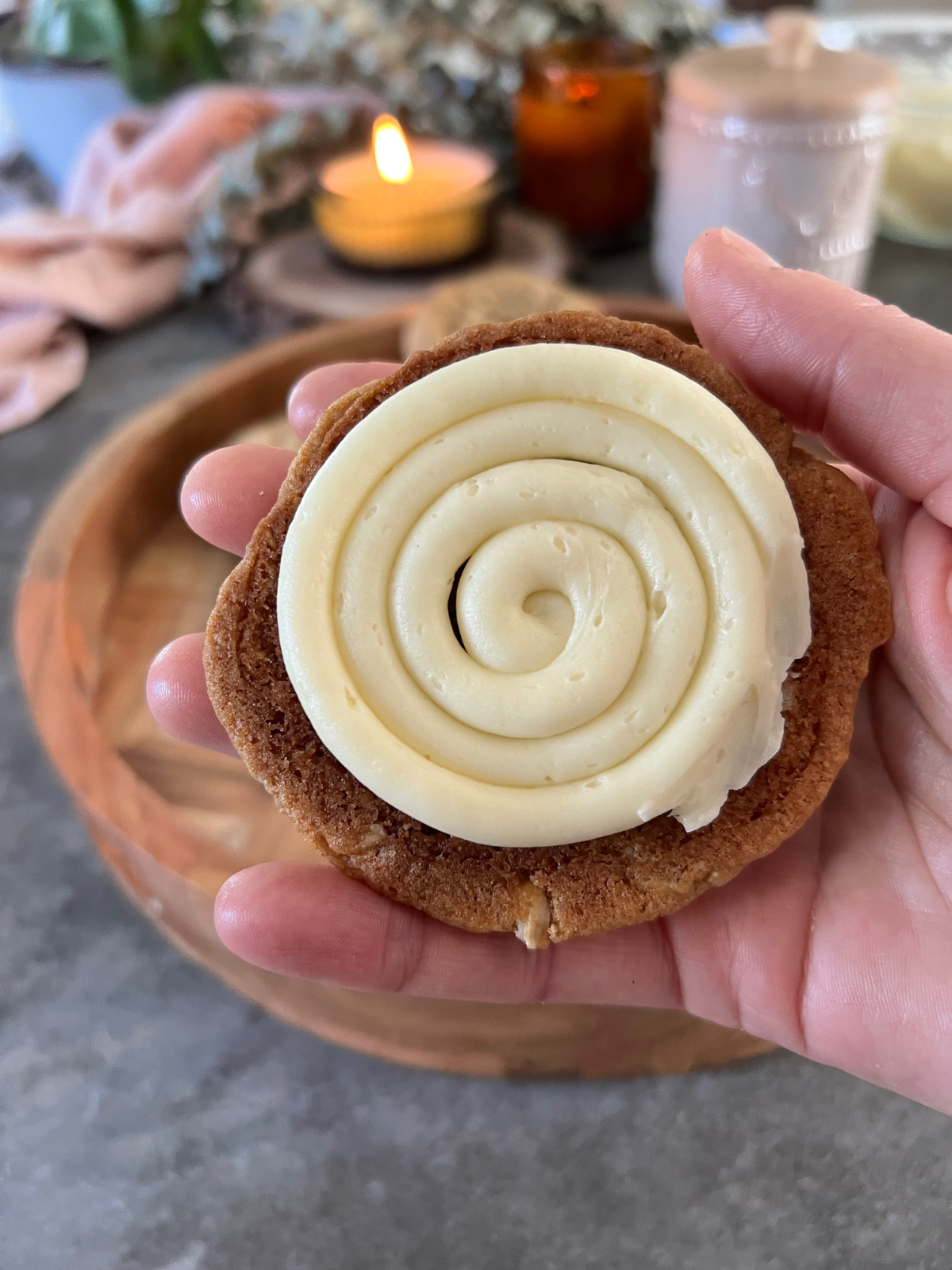 A sourdough oatmeal cookie has vanilla cream filling piped on the bottom of the cookie. It will be sandwiched together with another cookie to make a sourdough oatmeal cream pie.