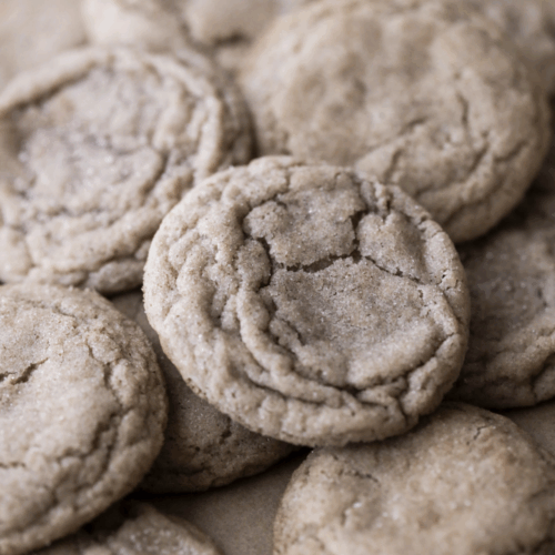 Many sourdough snickerdoodle cookies on parchment paper.