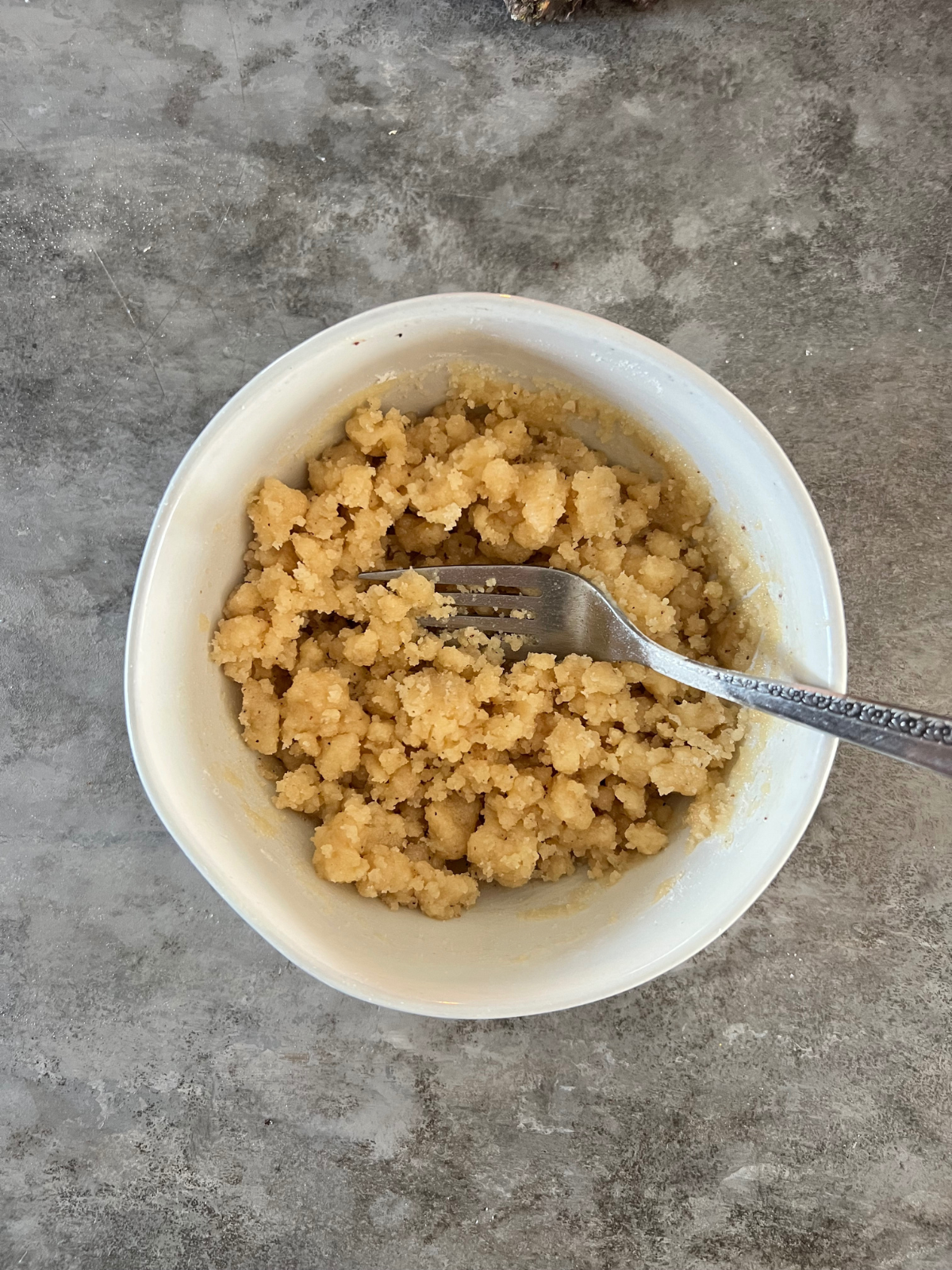 A small bowl holds the crumble topping for the sourdough vanilla bean muffins.