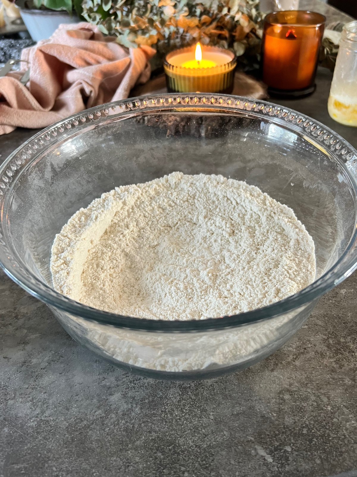A glass mixing bowl sits with the dry ingredients needed for the sourdough vanilla bean muffins.