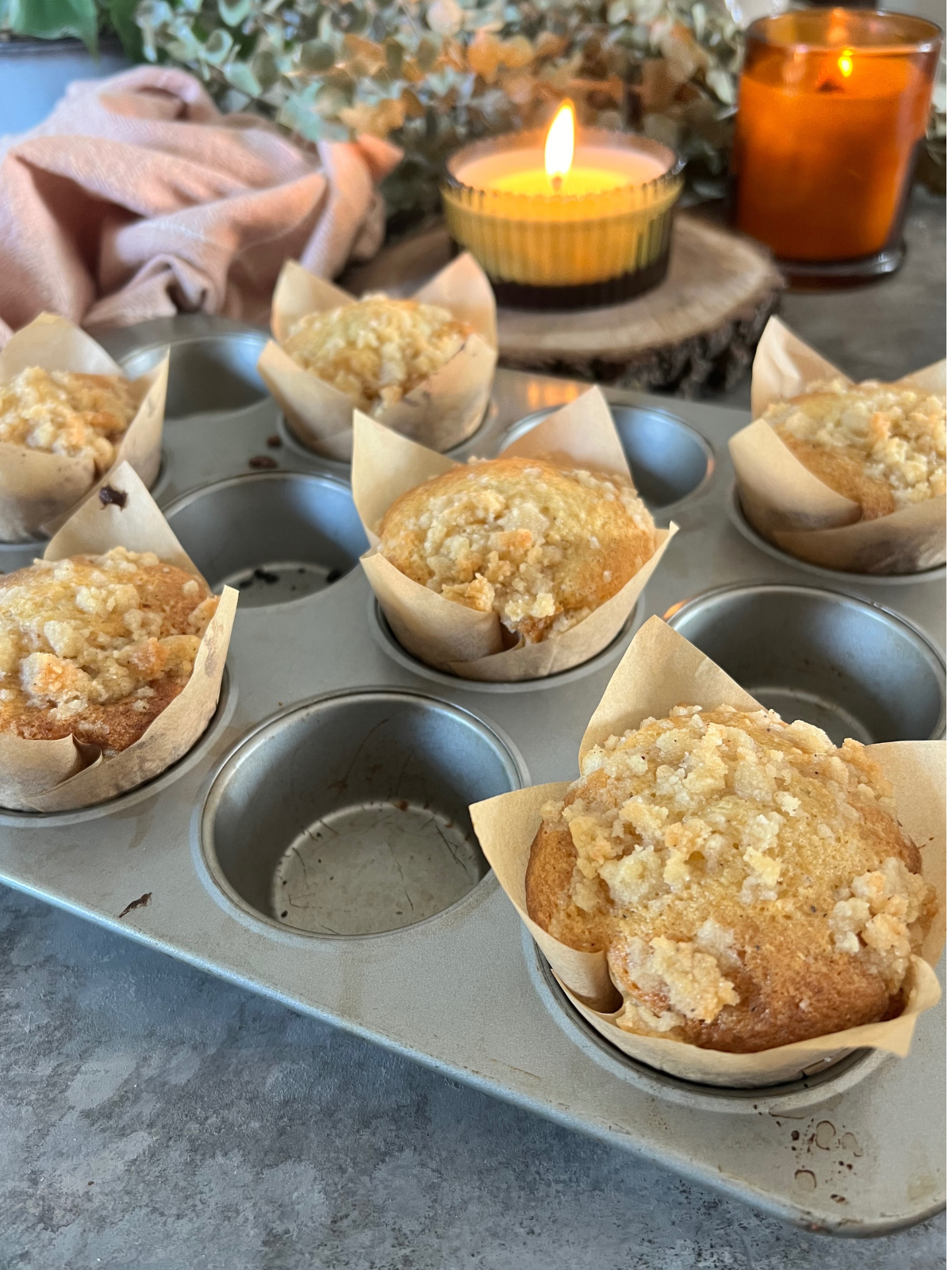 The baked sourdough vanilla bean muffins with crumble topping sit in the muffin tin.