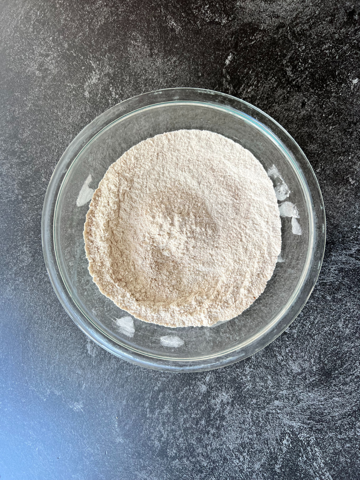 A medium sized mixing bowl with the dry ingredients needed for these sourdough snickerdoodles sits on the counter.