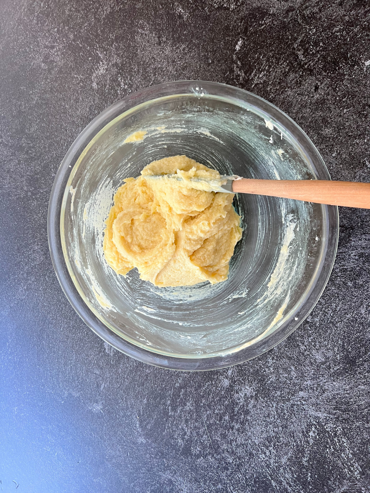 A glass mixing bowl sits with the wet ingredients for these sourdough discard snickerdoodles.
