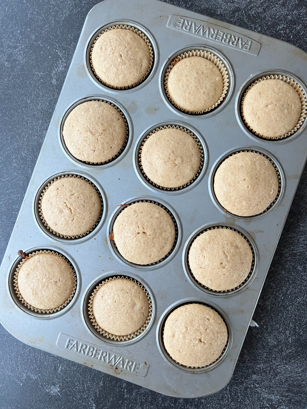 The sourdough snickerdoodle cupcakes have baked and are cooling in the muffin tin. 
