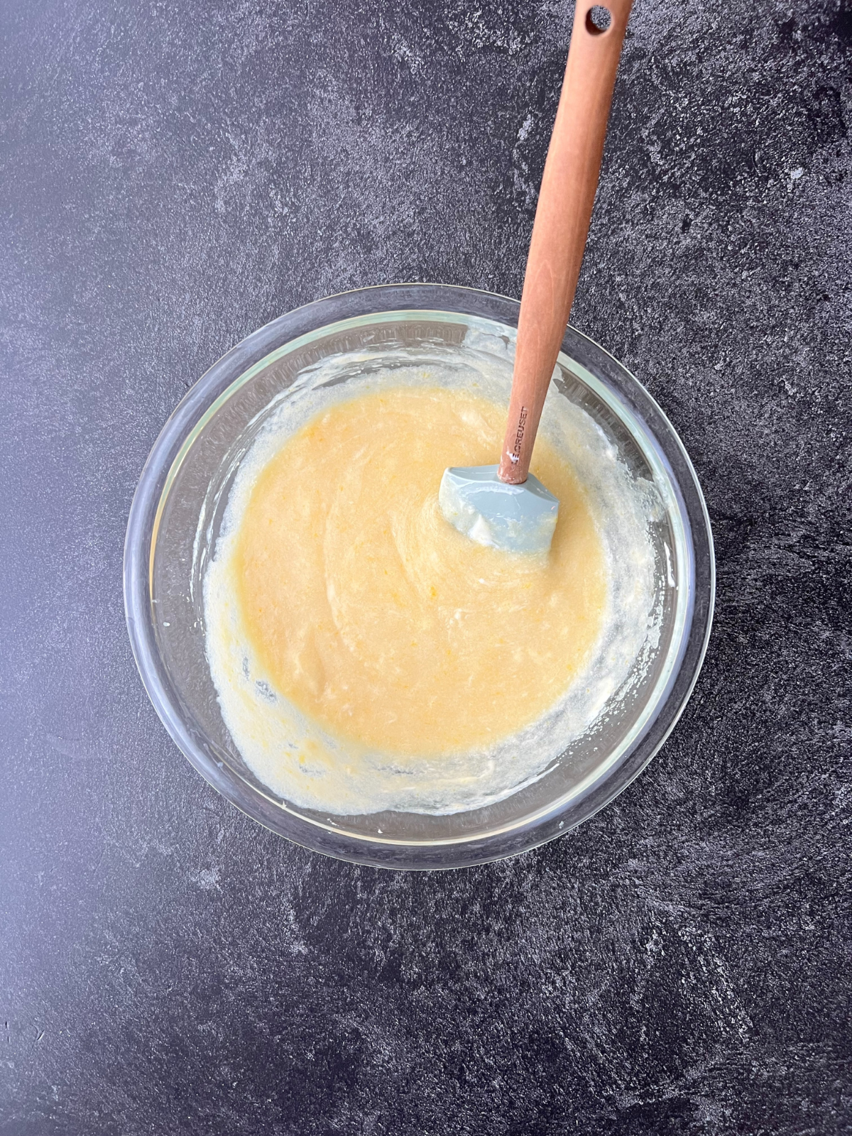 A glass mixing bowl sits with the wet ingredients needed for the sourdough snickerdoodle cupcakes. 