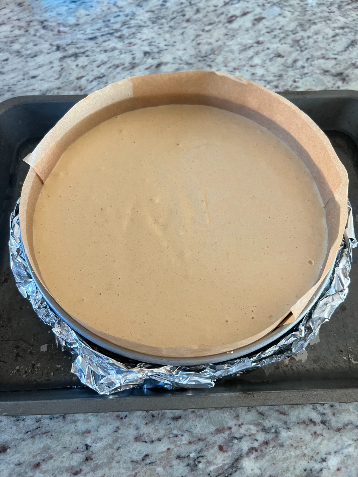 The pre-baked pumpkin cheesecake with sourdough graham cracker crust sits in a water bath before heading into the oven. 