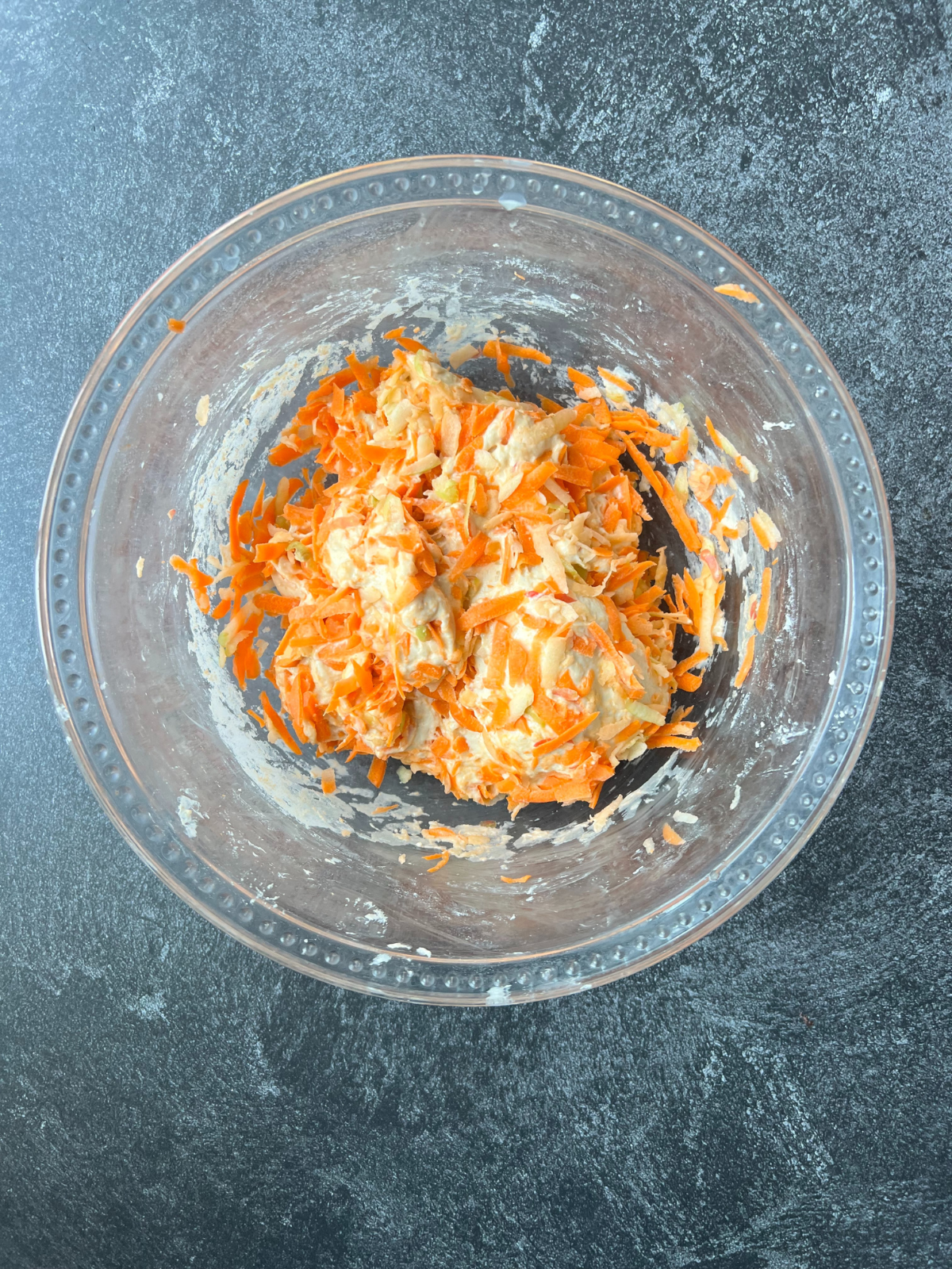 A bowl of the fermented dough with the shredded carrots and apples in it.