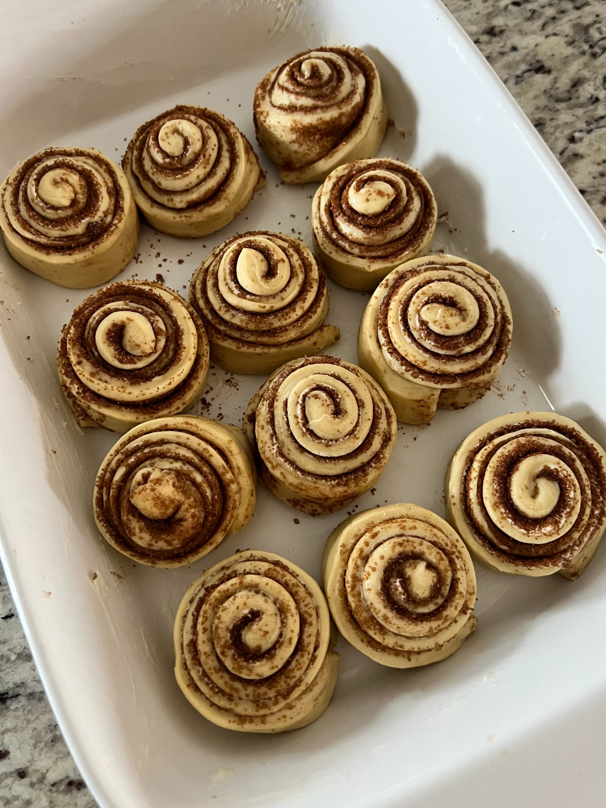 The sourdough brioche cinnamon rolls sit in a greased 9x13 inch baking dish preparing for their second rise.