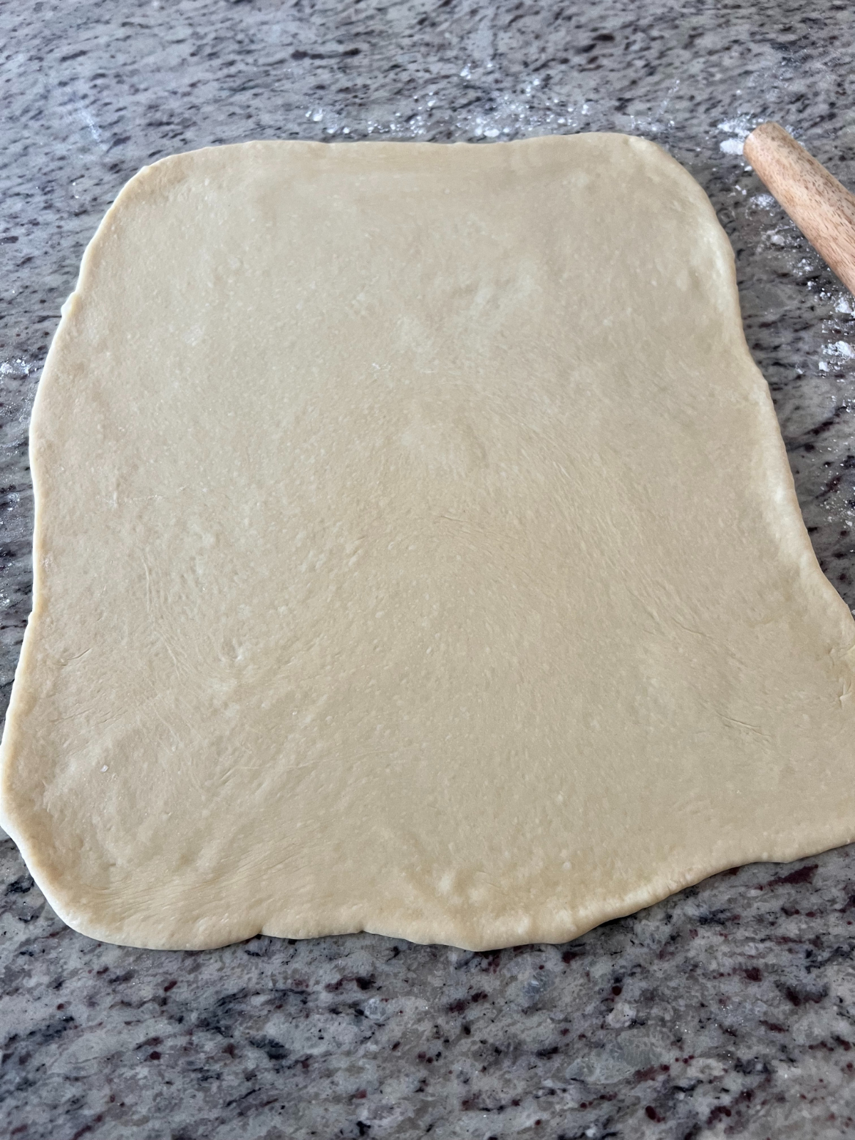 The sourdough brioche cinnamon roll dough is shown rolled out into a 12x18 inch rectangle.