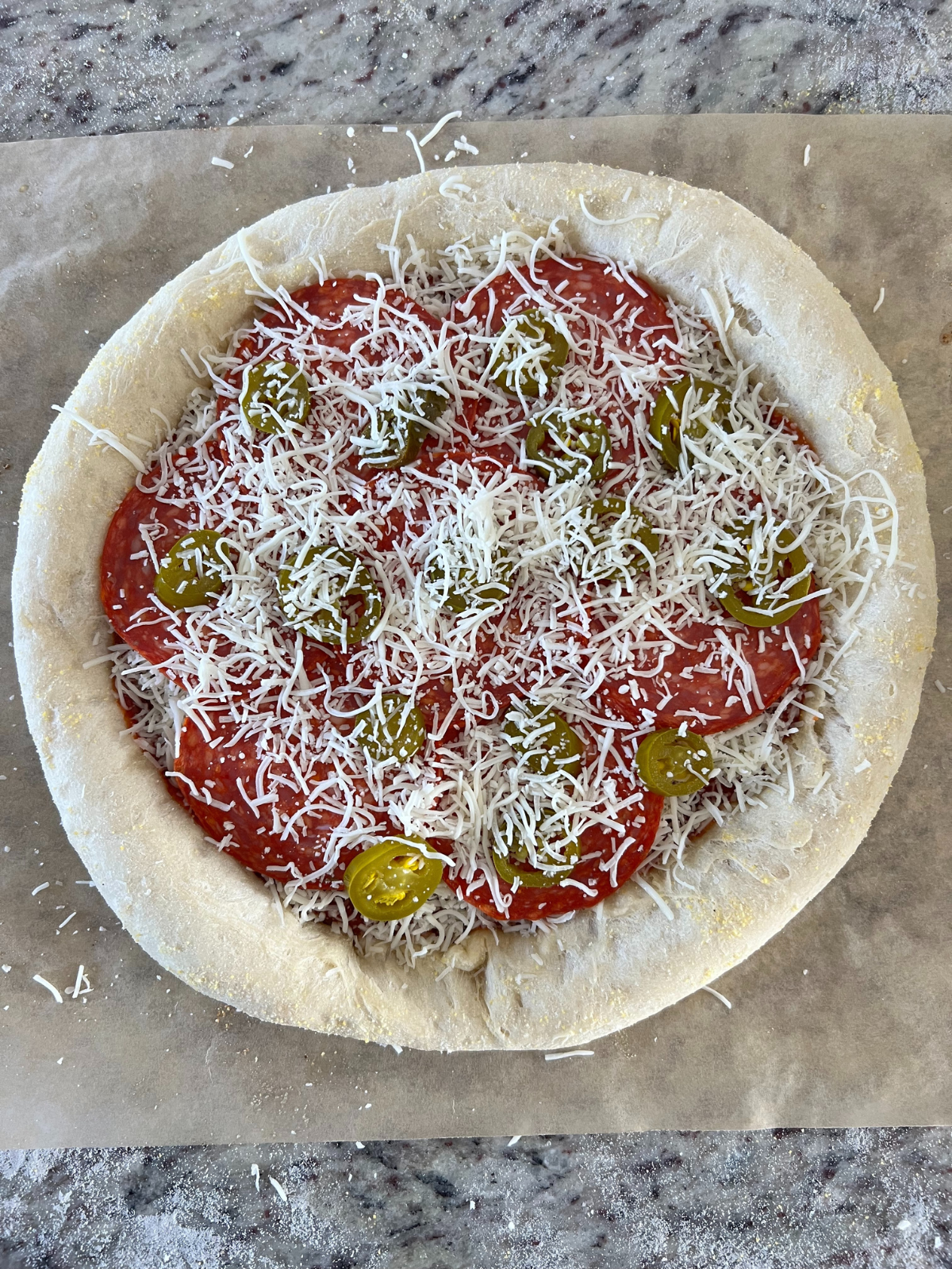 The naturally fermented sourdough pizza crust has cheese, jalapenos, and pepperoni on it preparing for the complete bake.