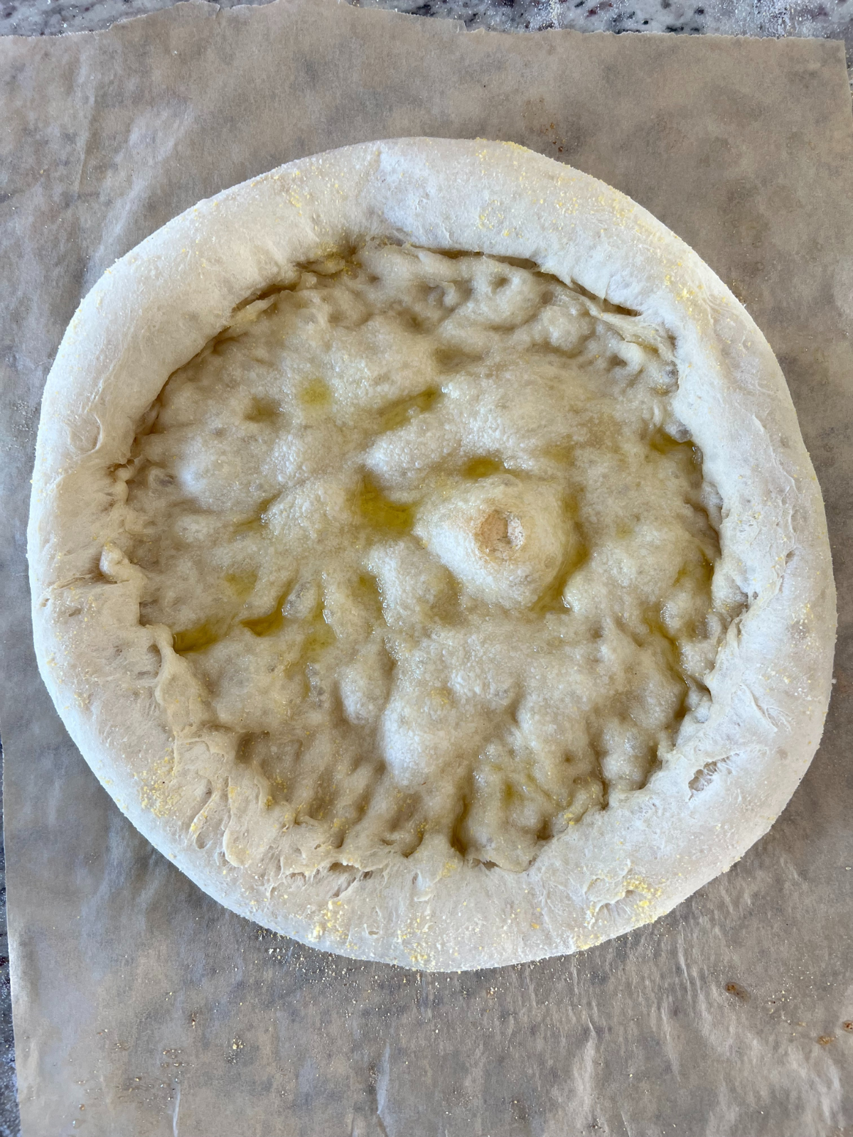 The par-baked sourdough pizza crust sits on parchment paper.
