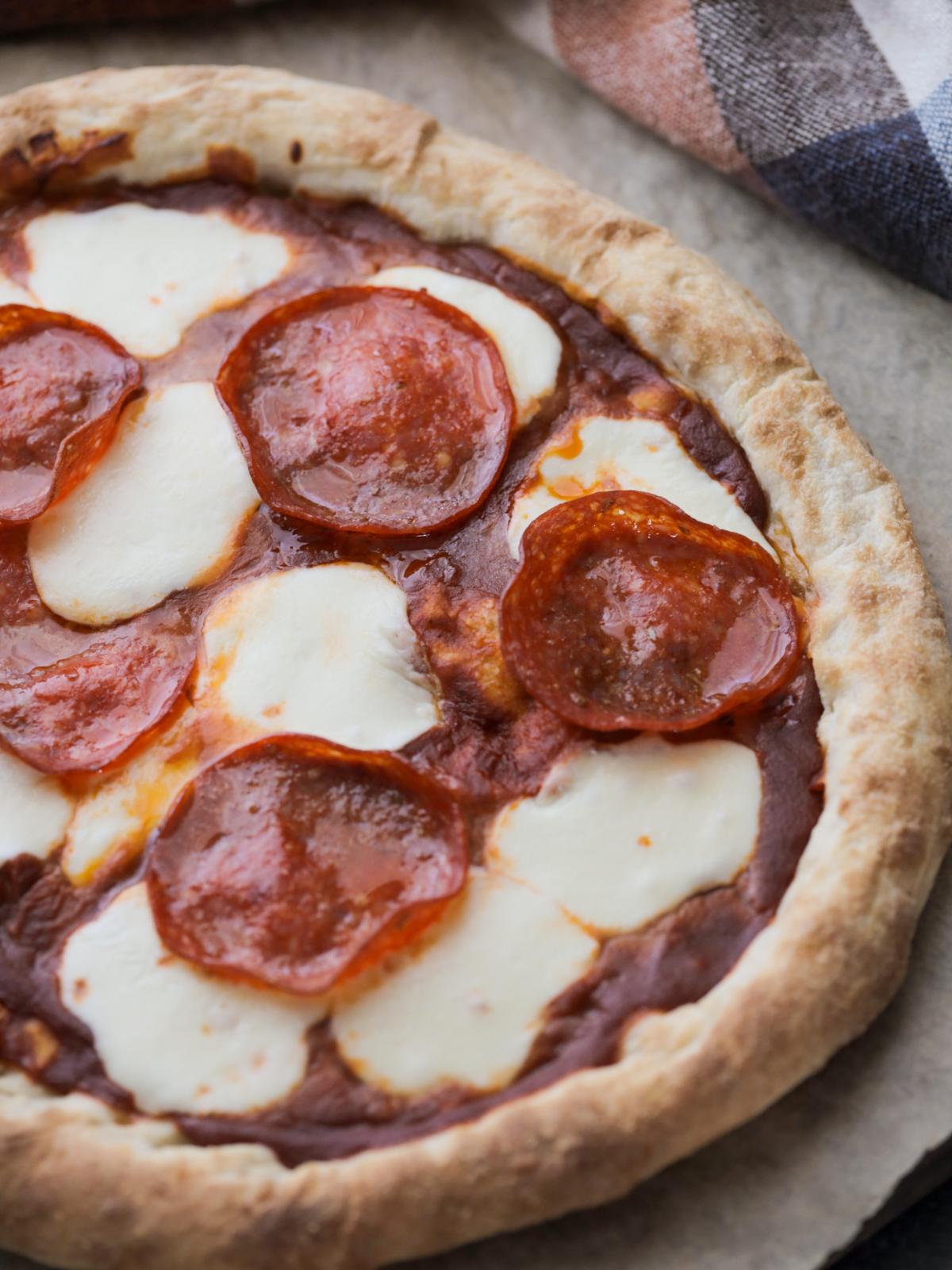 A close up of freshly baked sourdough pizza crust with pepperoni and mozzarella cheese. 