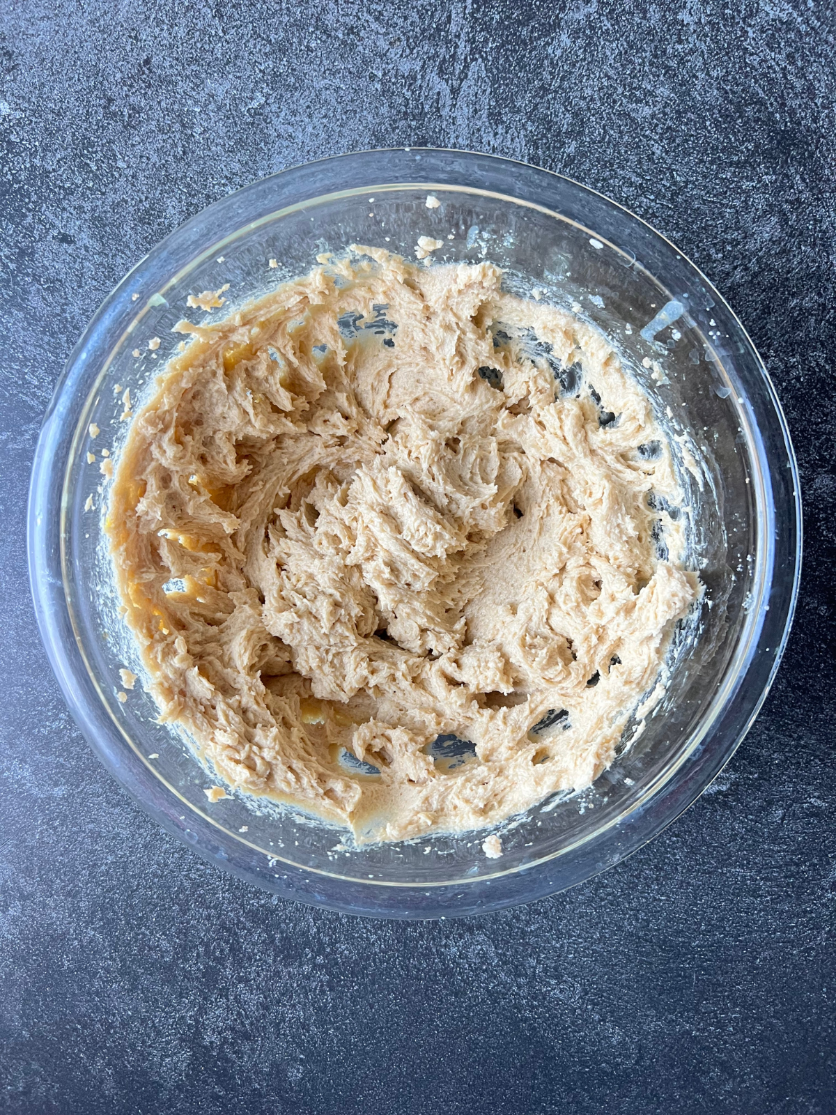 A glass mixing bowl sits with creamed butter and sugars.