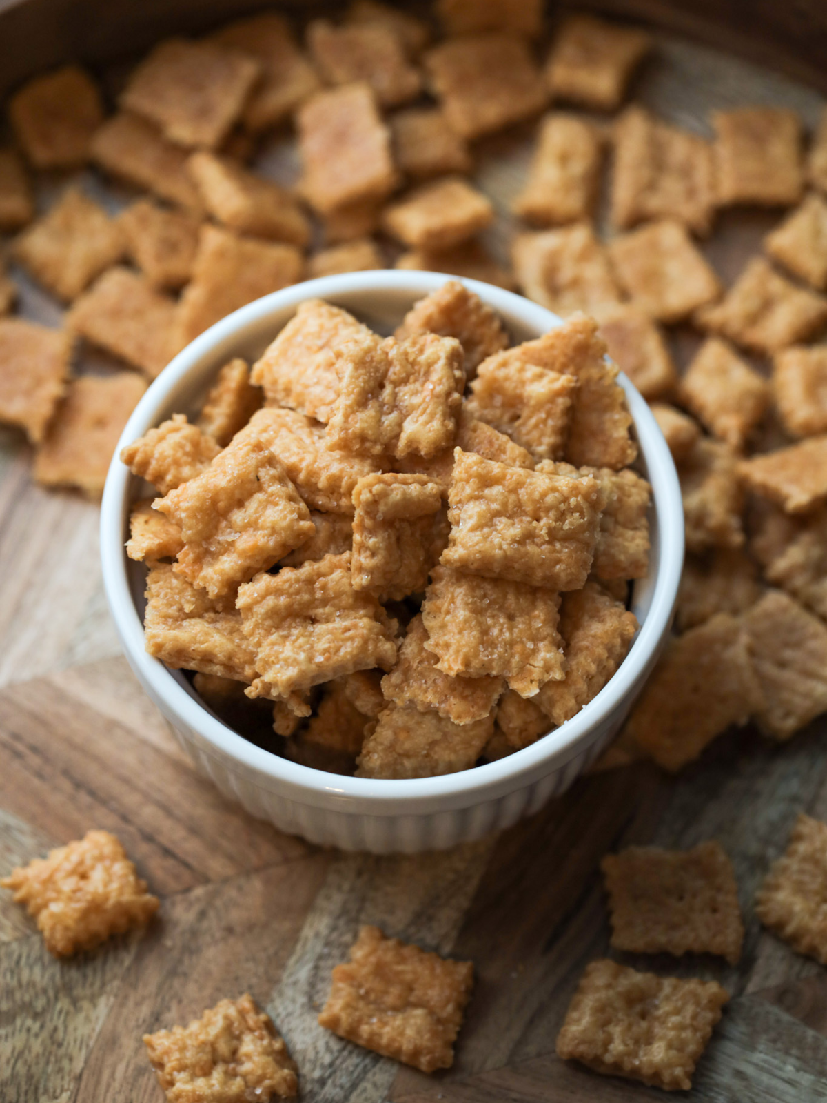 The fully baked sourdough discard cheez-it's sit in a bowl with many others scattered around.
