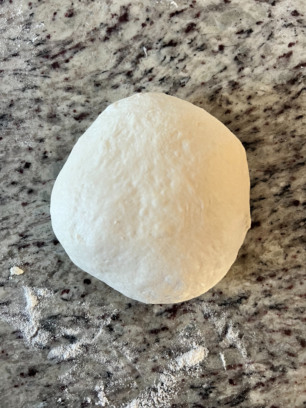 Soft sourdough sandwich bread dough sits in a pre-shaped rolled ball. 