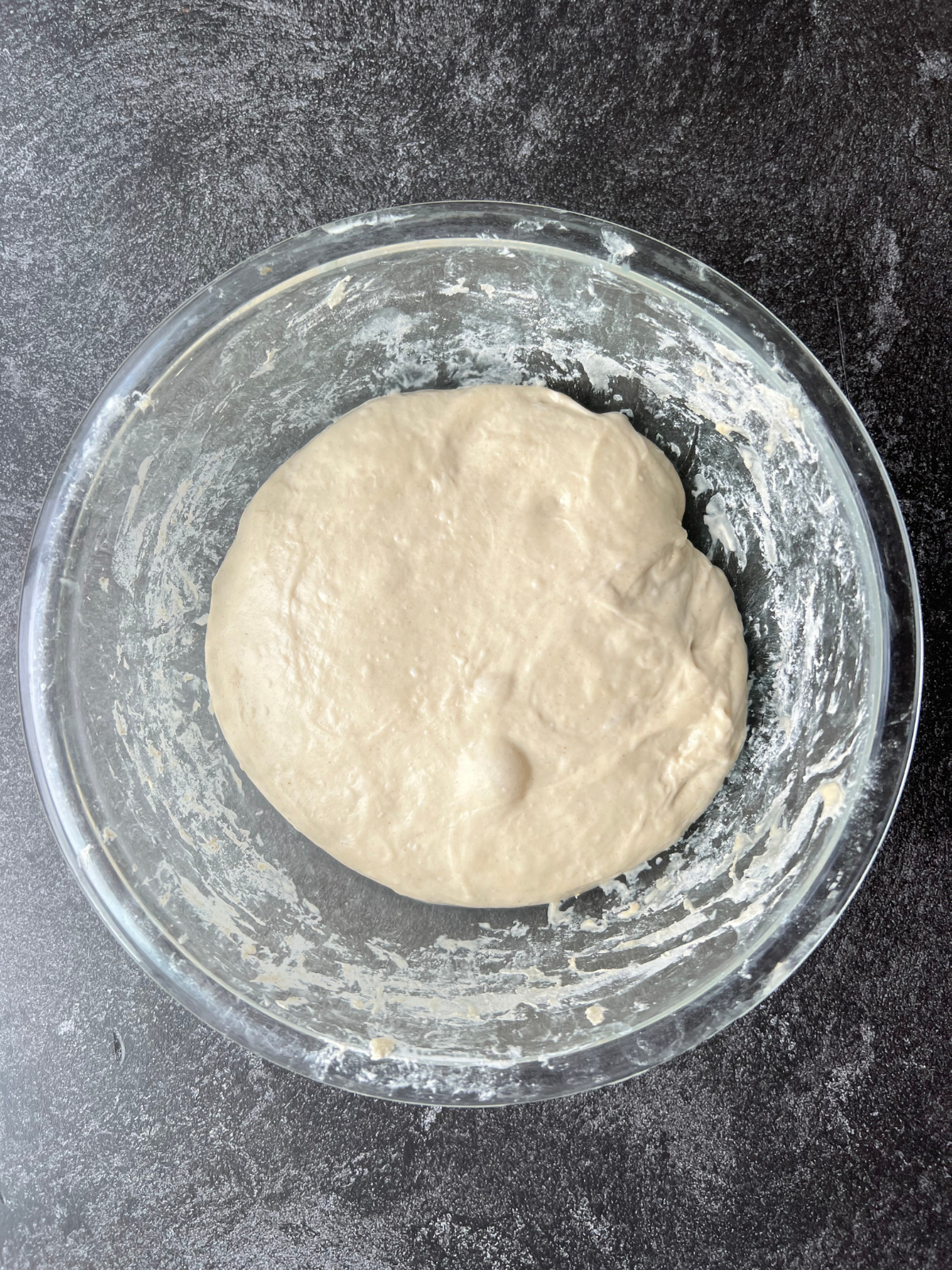 Sourdough dough bulk fermenting in a glass mixing bowl.