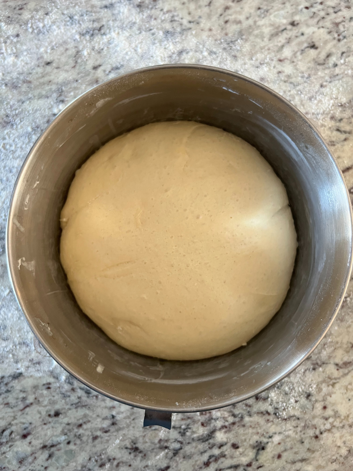 The risen sourdough donut dough has nearly doubled in size and sits in the mixing bowl.