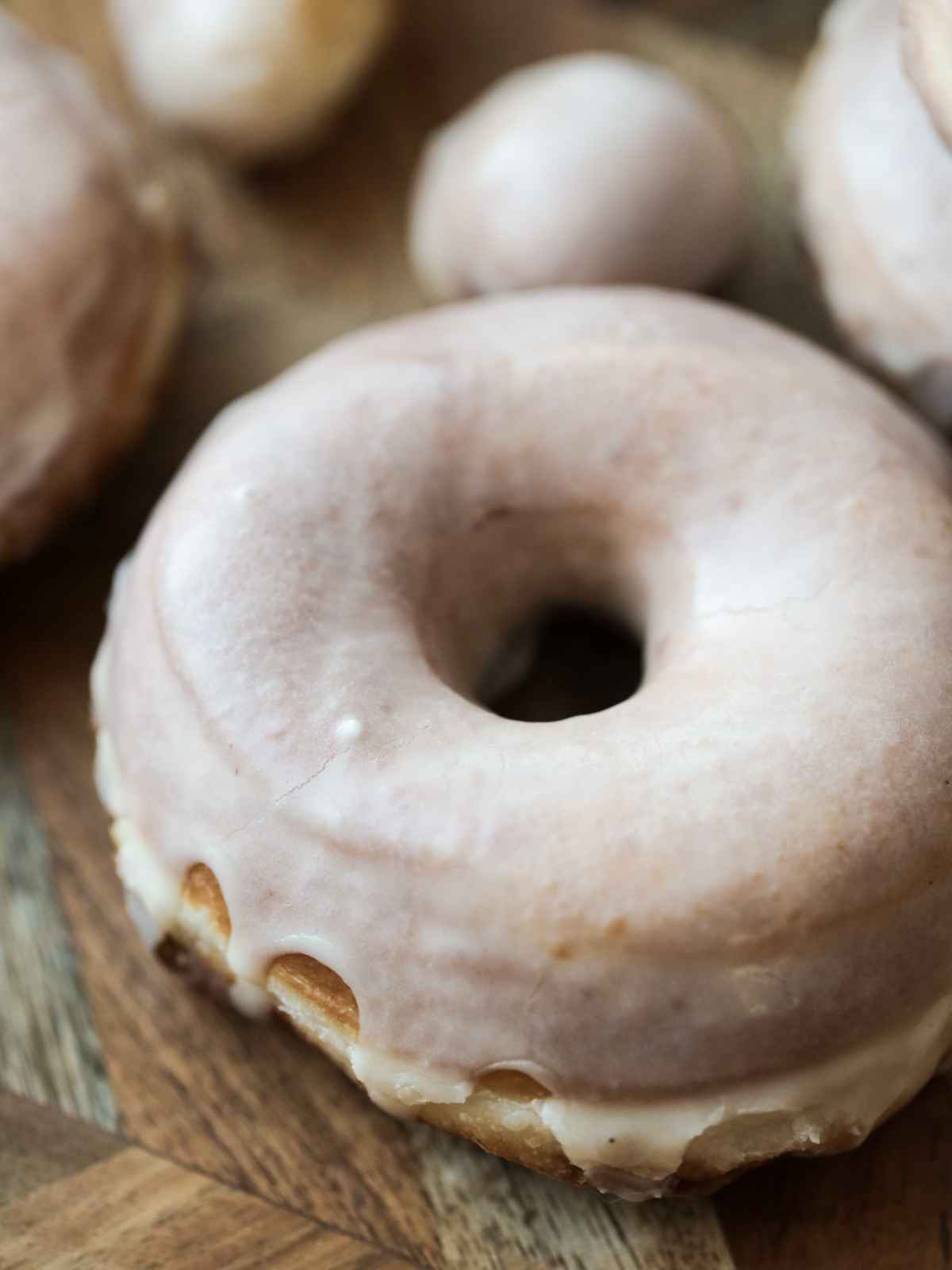 One sourdough glazed donut with several in the background.