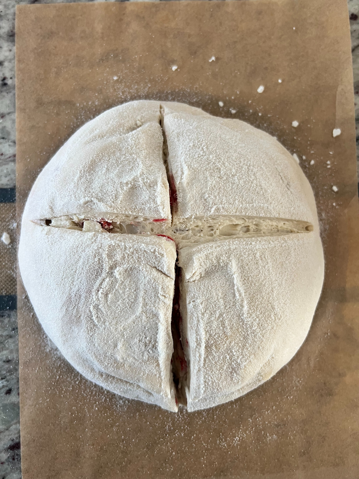 The sourdough strawberry white chocolate bread dough has been scored crisscross, preparing to bake.