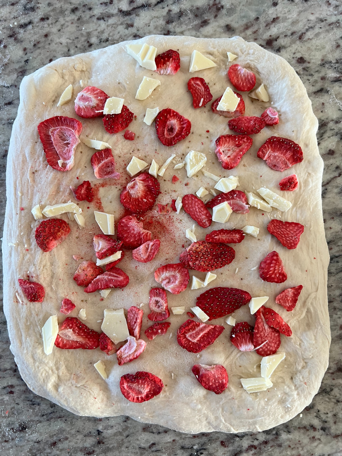 The sourdough dough is covered with chopped white chocolate and freeze-dried strawberries.