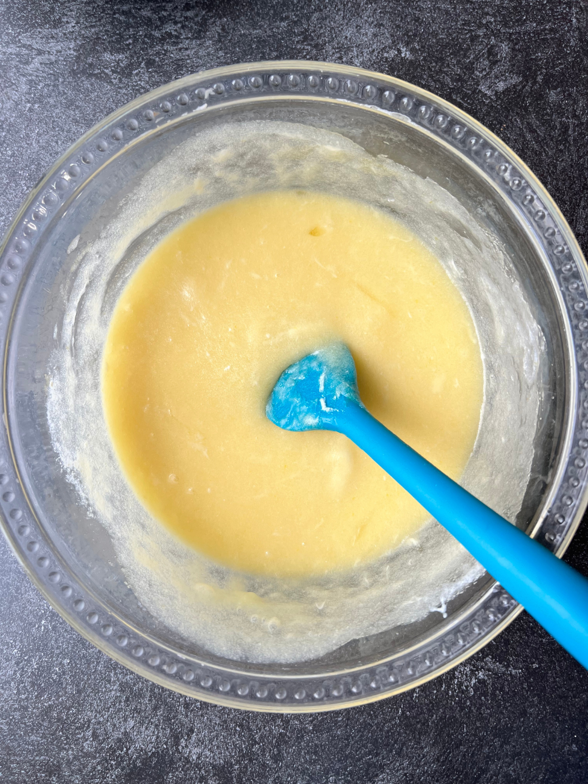 A glass mixing bowl sits with the wet ingredients needed for the sourdough vanilla birthday cake. 