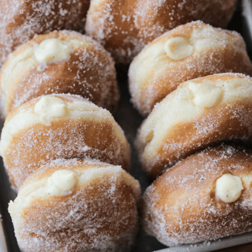 Eight sourdough discard vanilla custard filled donuts sit in a pan.