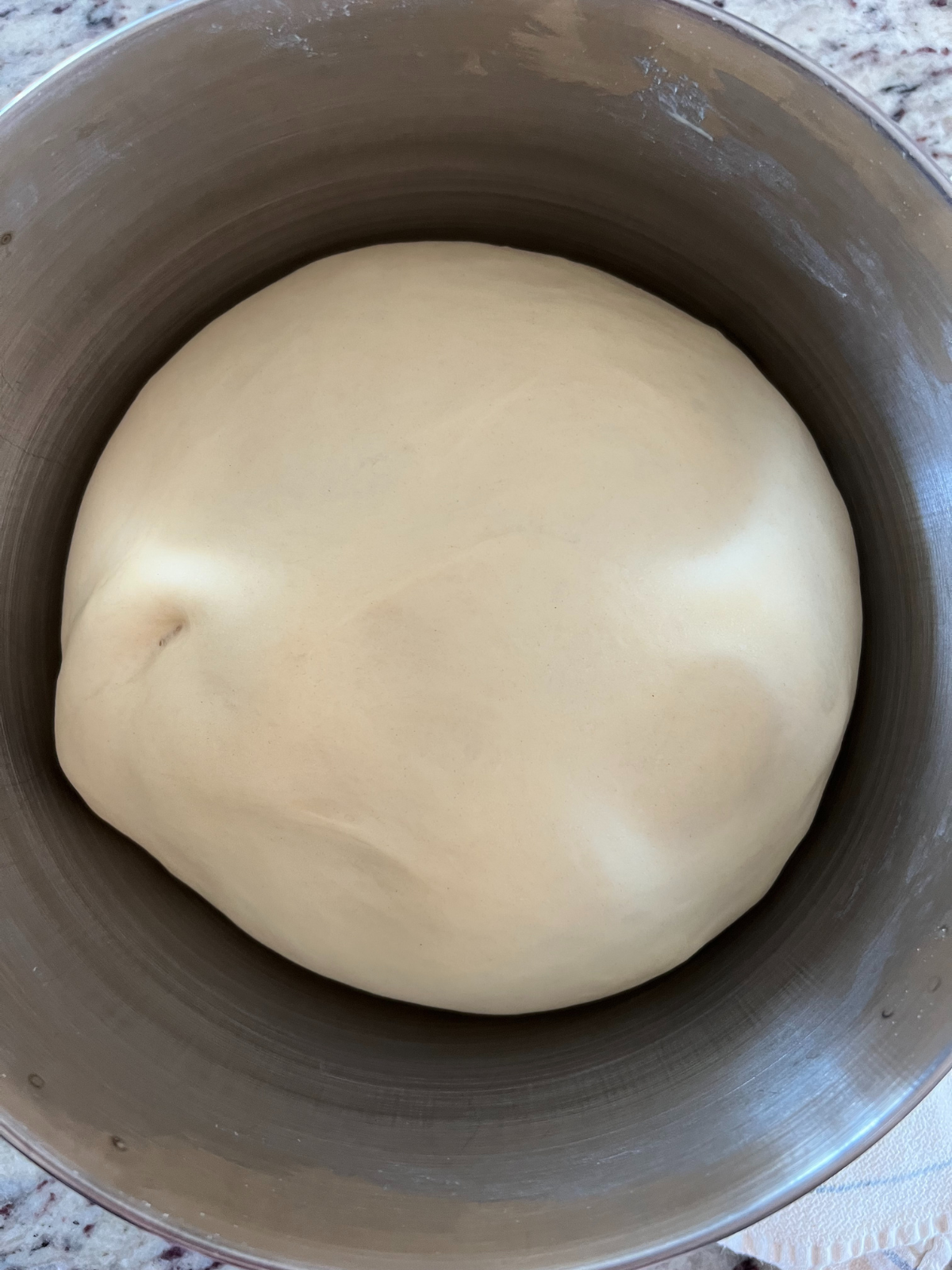 The doubled and risen sourdough donut dough sits in a mixing bowl.