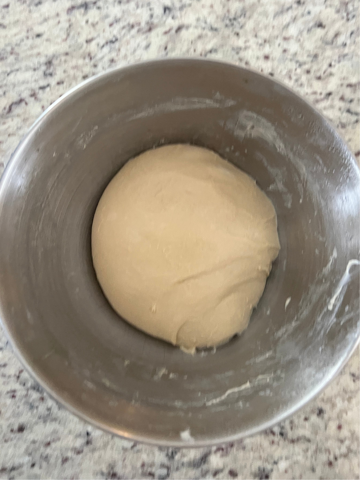 Sourdough brioche dinner roll dough sit in the bowl of a stand mixer after being knead for about 7 minutes. 