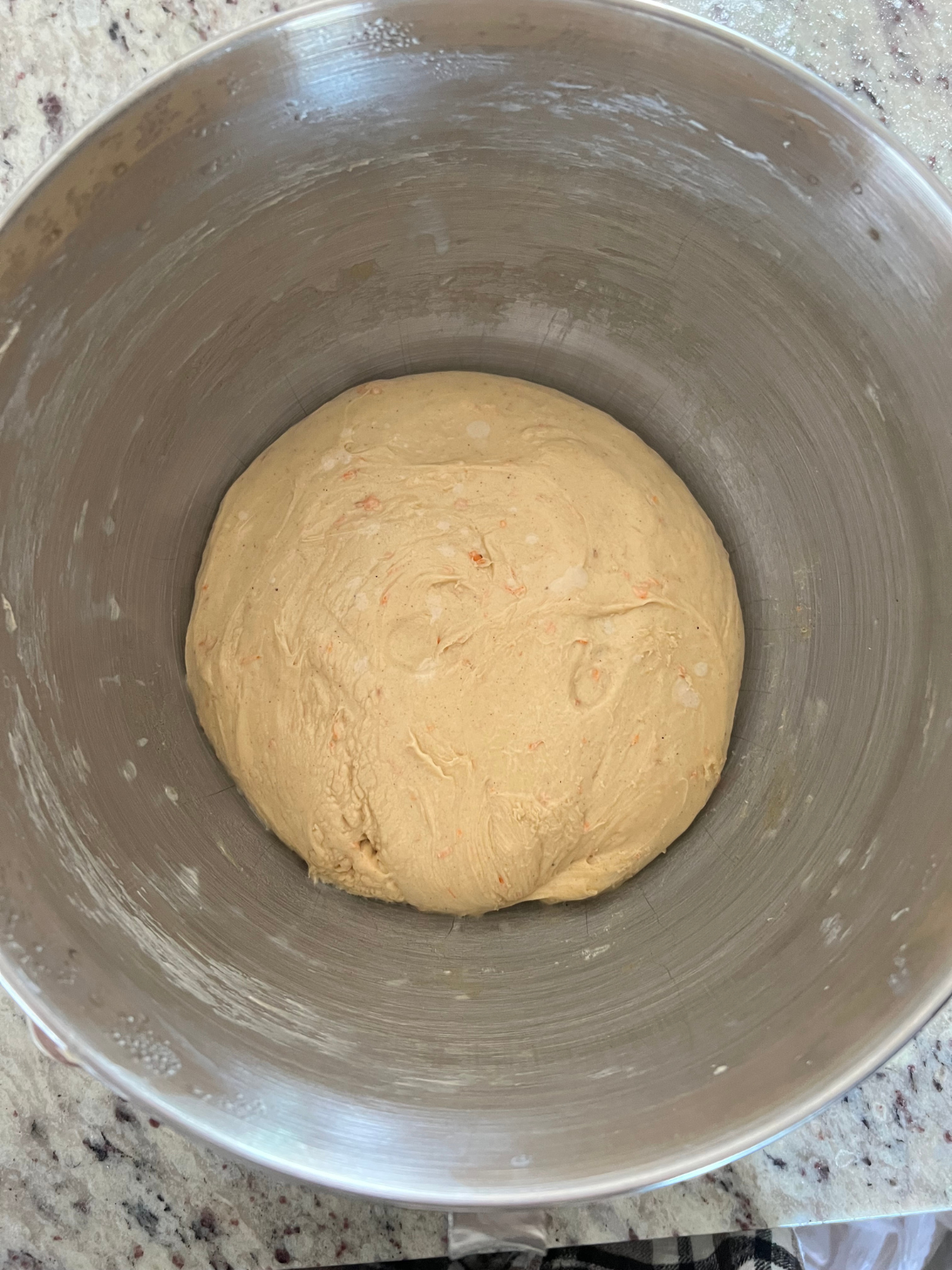 The sourdough carrot cake dough sits in the mixing bowl of a stand mixer.