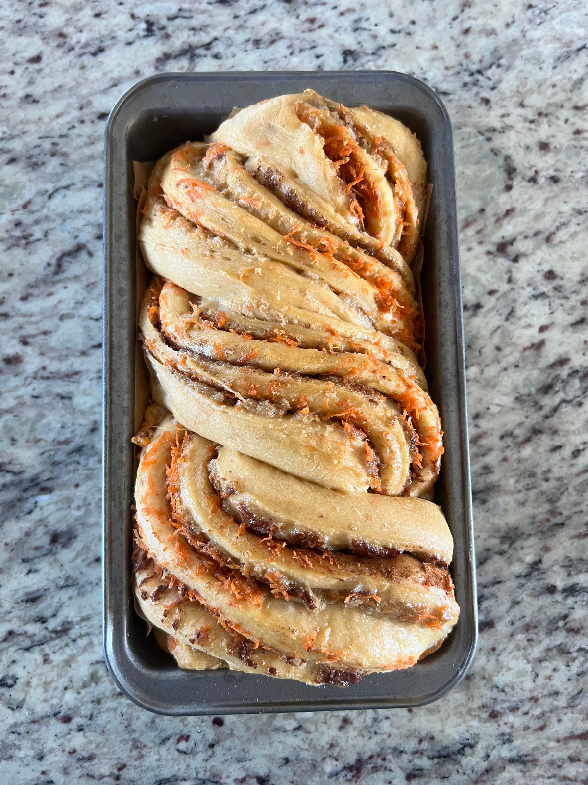 The sourdough carrot cake babka is shown in the loaf pan after its second rise.