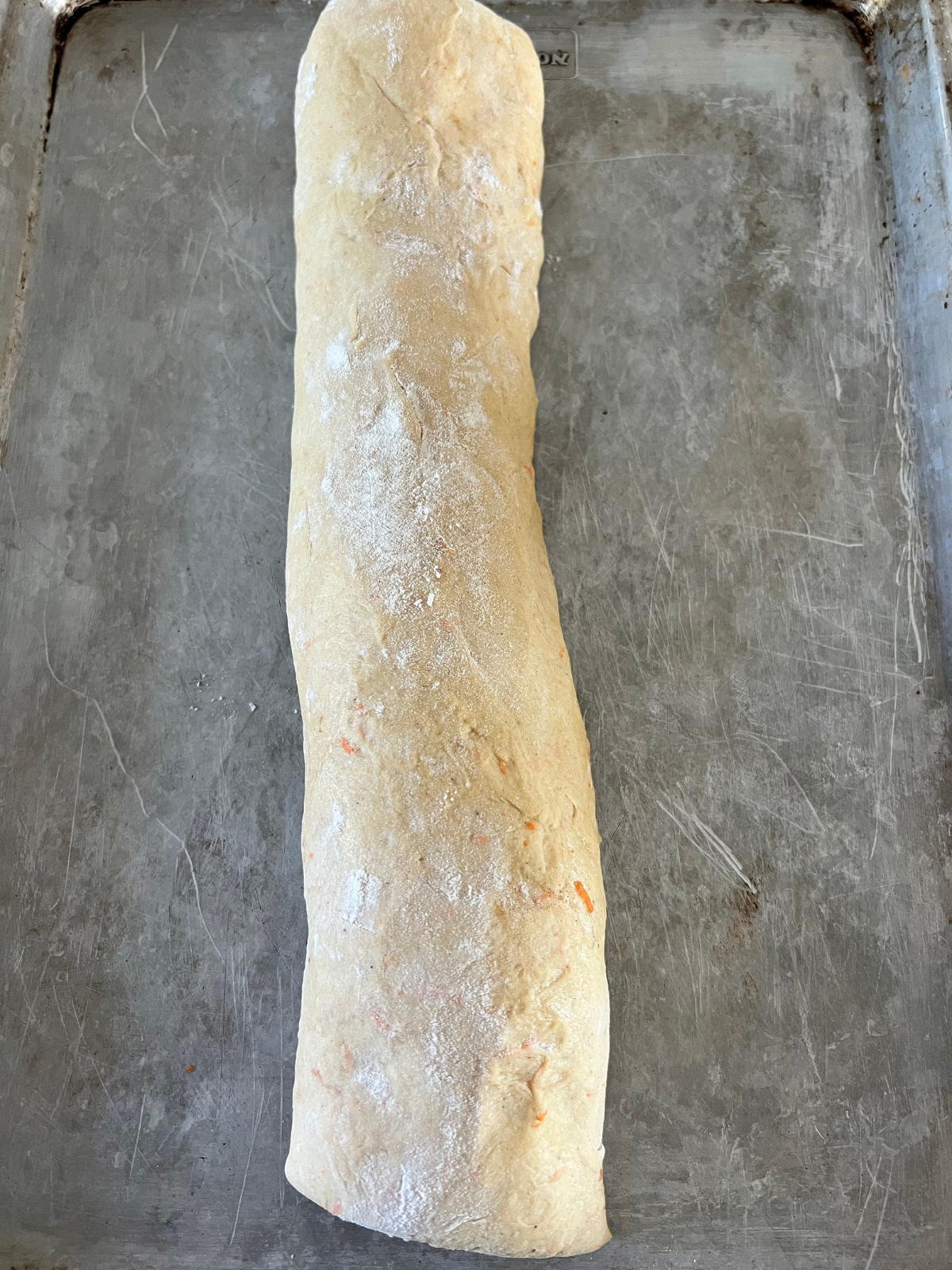 The sourdough carrot cake babka dough has been rolled into a log lengthwise.