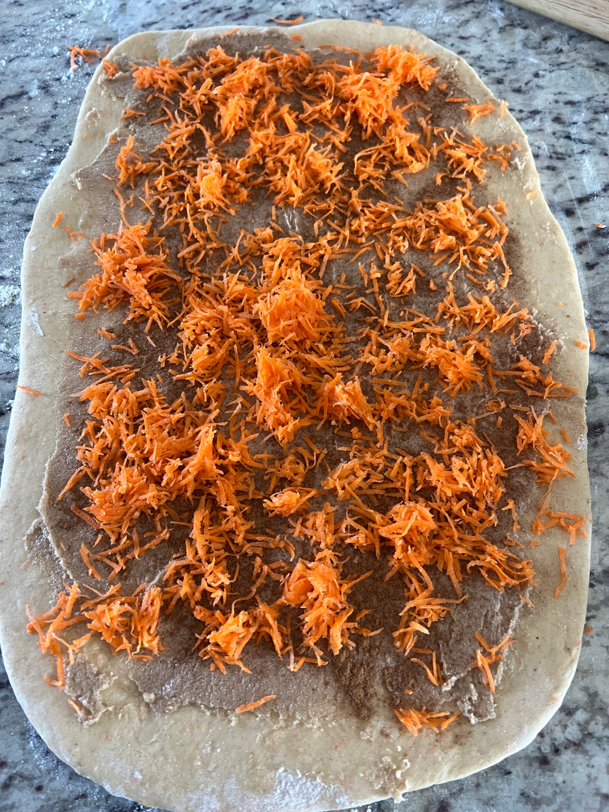 The sourdough carrot cake babka dough is rolled into a rectangle and topped with carrots and the cinnamon sugar filling.