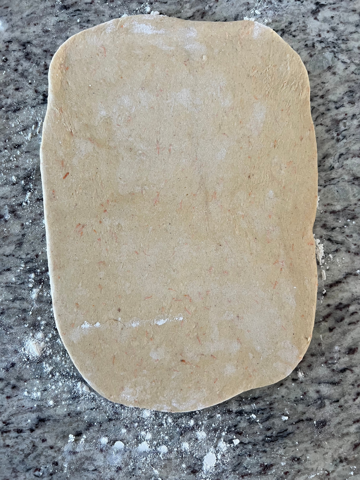 The sourdough cinnamon carrot cake babka dough is shown rolled into a rectangle preparing for the carrot cake filling.
