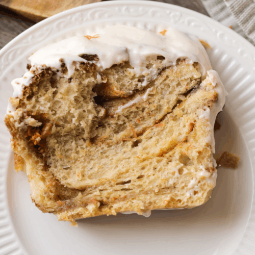 A slice of sourdough carrot cake babka with frosting lays on a plate.