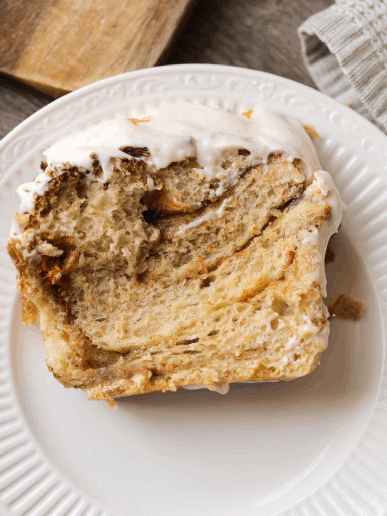 A slice of sourdough carrot cake babka with frosting lays on a plate.