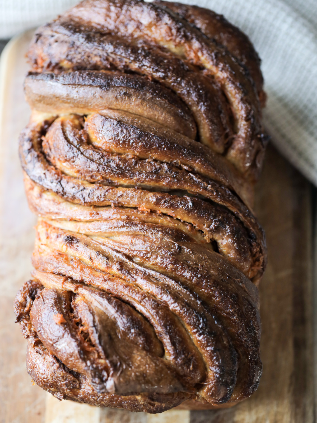 Sourdough carrot cake babka sits on a wooden cutting board fresh out of the oven.