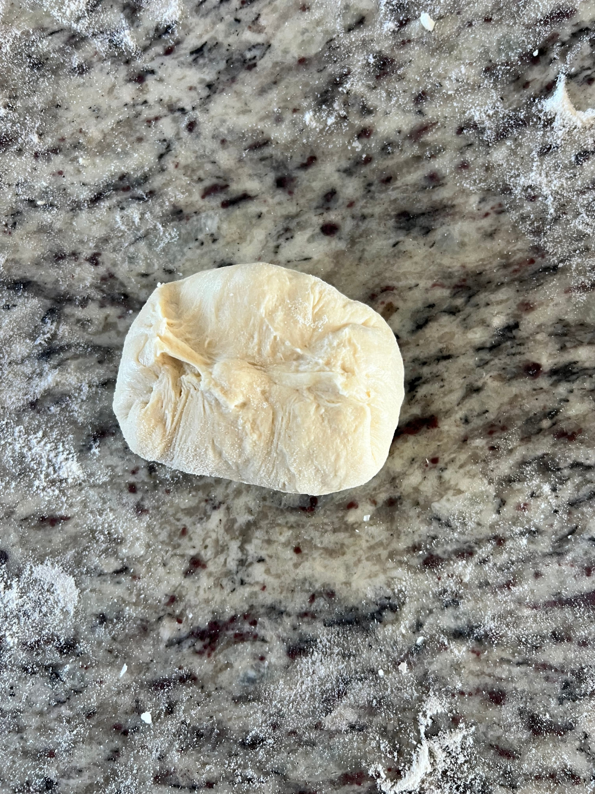 The sourdough naan dough ball seams have been pinched together to keep all the cheese within.