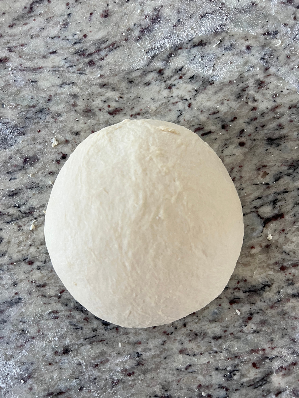 The sourdough naan dough has been kneaded into a round dough ball.